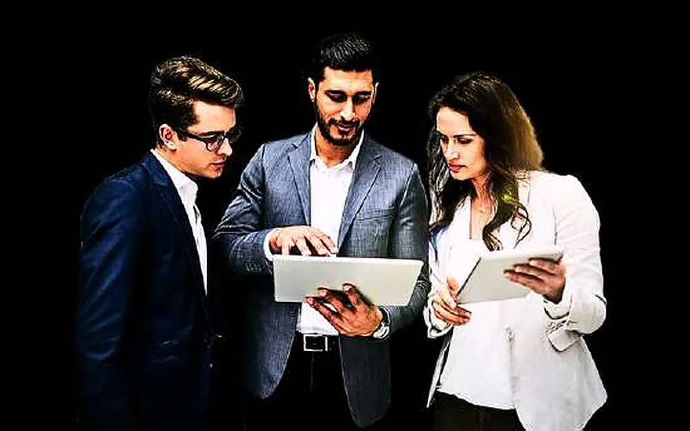 Colleagues from different teams comparing notes on tablets during a project review